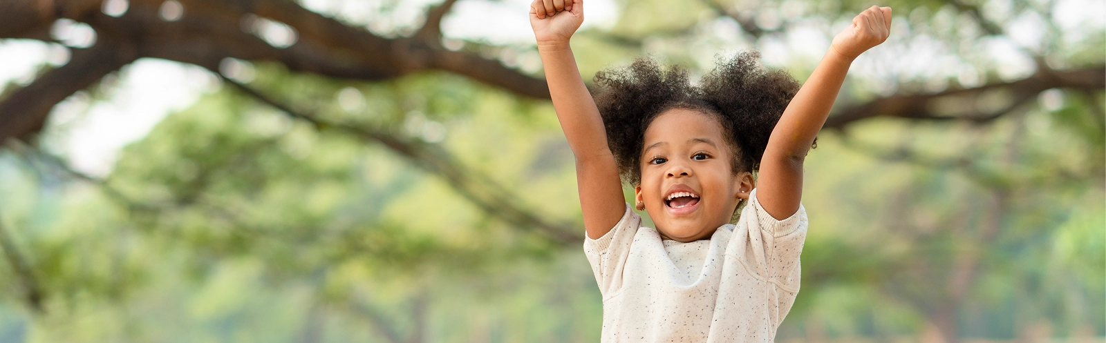 happy-african-american-little-girl-smiling-raises-her-hand-while-sitting-park