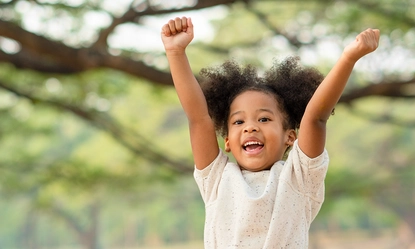 happy-african-american-little-girl-smiling-raises-her-hand-while-sitting-park