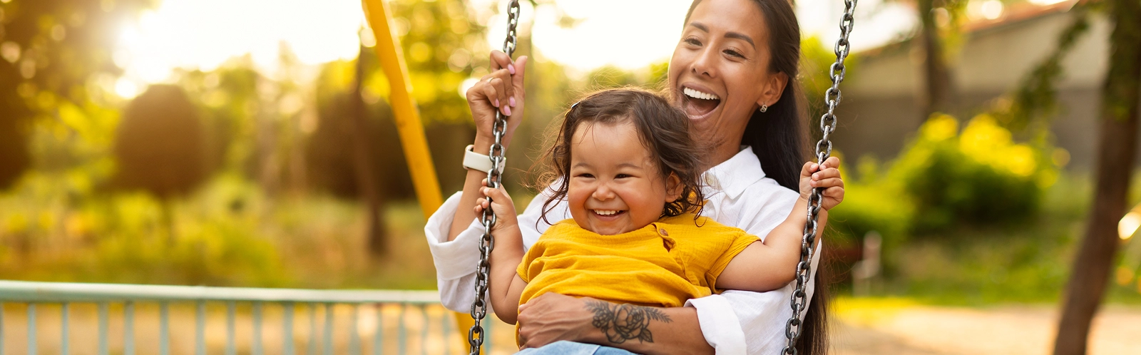japanese-mom-sitting-with-toddler-infant-daughter-swinging-playground