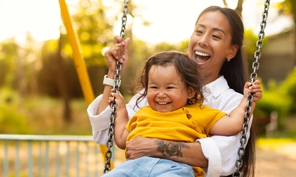 japanese-mom-sitting-with-toddler-infant-daughter-swinging-playground