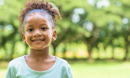portrait-african-american-little-girl-with-curly-hair-smiling-looking-camera-park