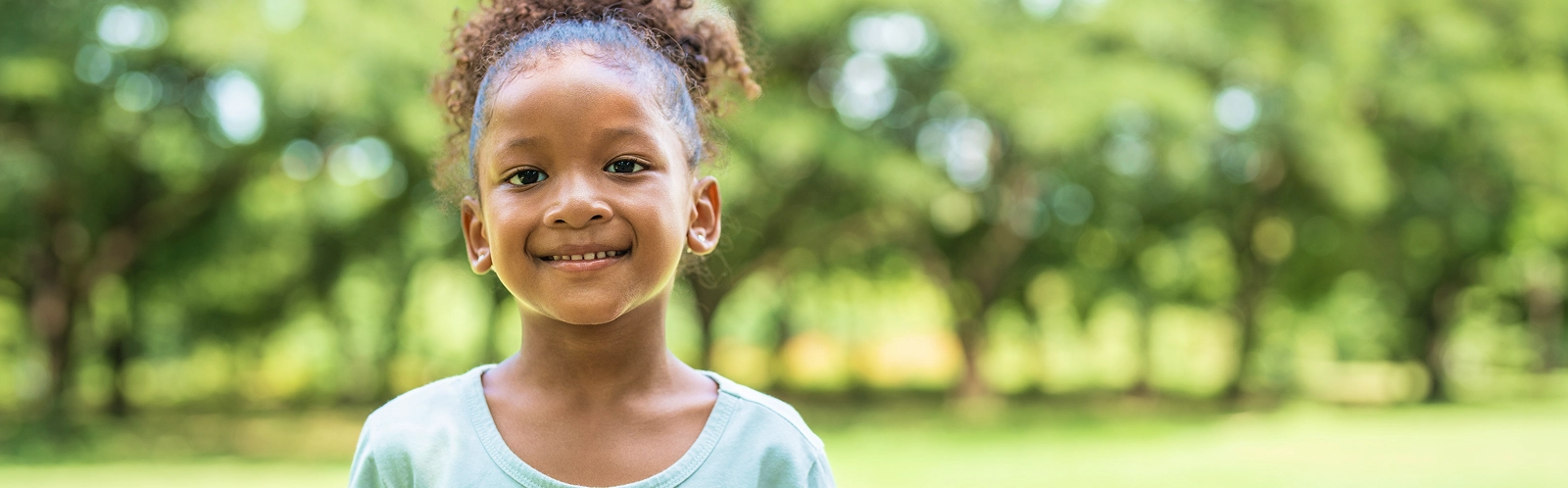 portrait-african-american-little-girl-with-curly-hair-smiling-looking-camera-park