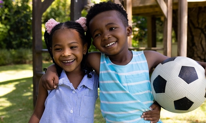 portrait-smiling-african-american-siblings-with-soccer-ball-standing-park
