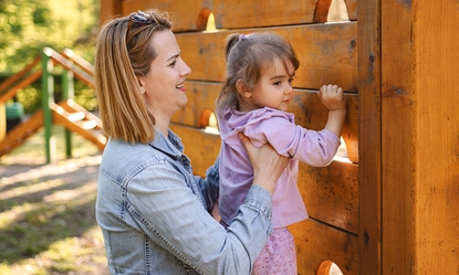 smiling-mom-helps-her-cute-daughter-climb-playground (1)