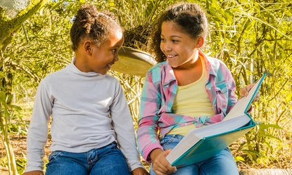 young-sisters-with-book-sitting-tree
